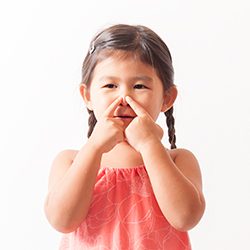 Young girl with braids smiling and putting her index fingers on her nose