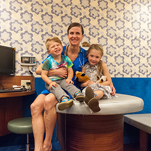Nurse Practitioner Bridget (Bridie) Hatch smiling and posing with two young kids sitting on an exam table at a Tribeca Pediatrics office