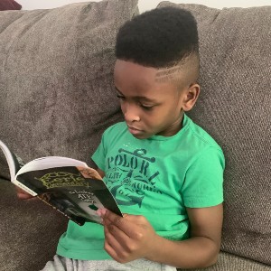 Young boy sitting on a couch reading a book