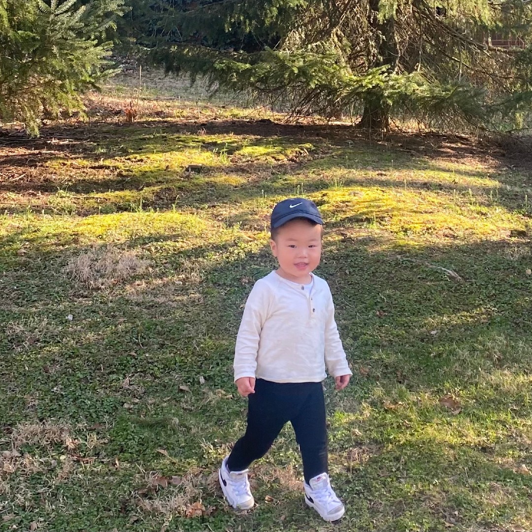 Young boy smiling and standing in a grassy yard