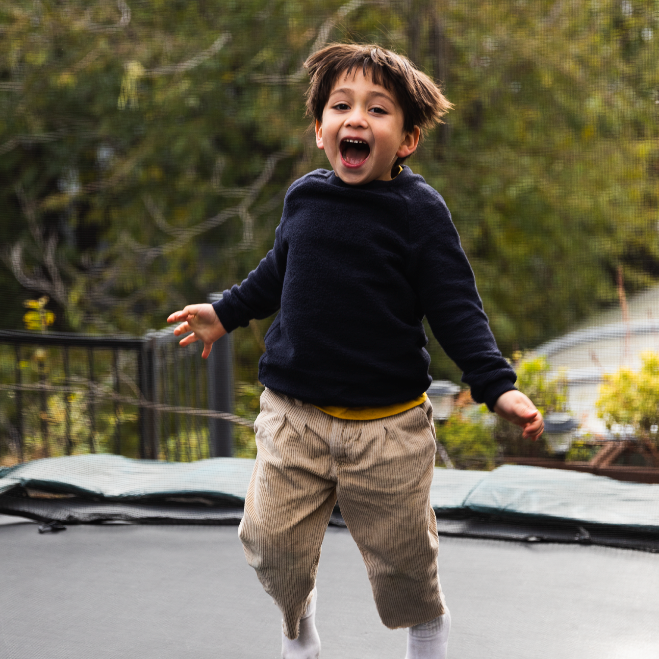 Young boy jumping on an outdoor trampoline and smiling