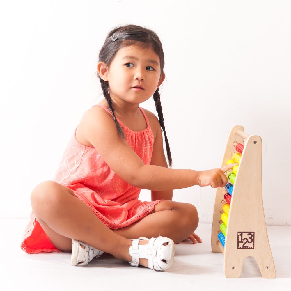 Young girl who looks unsure of herself playing with an abacus
