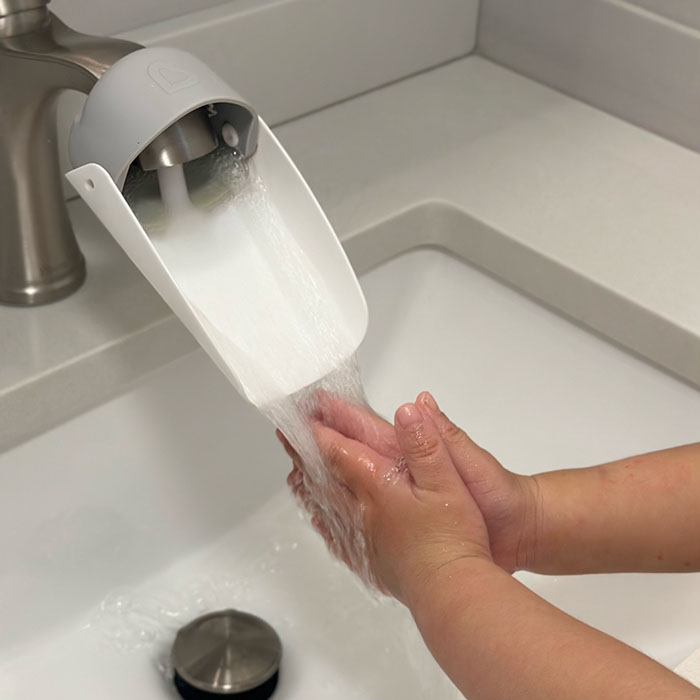Child's hands running under water in a sink
