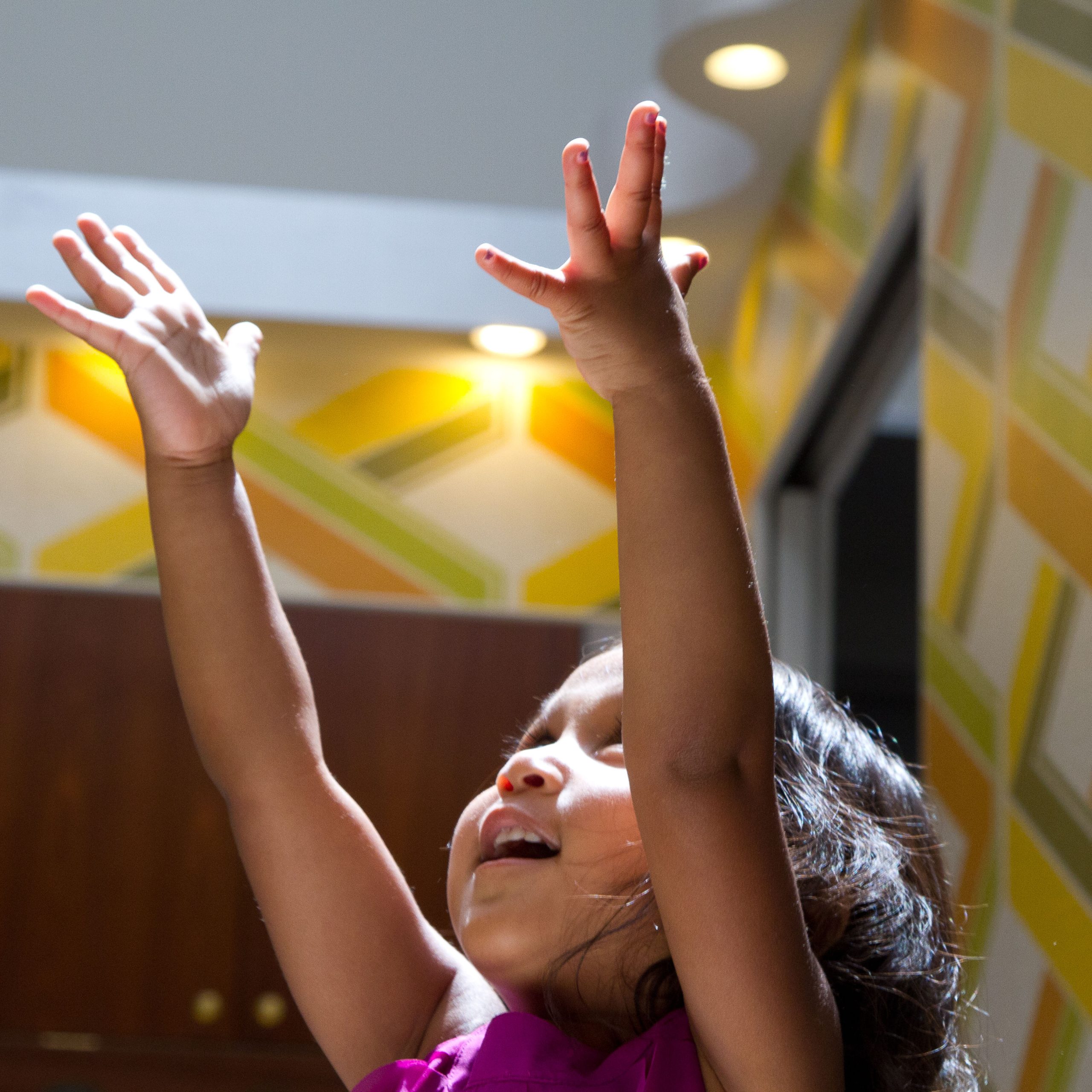 Young girl reaching her arms up toward the ceiling and smiling